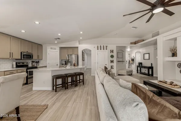 a living room with stainless steel appliances furniture and a kitchen view