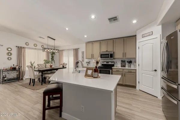 a kitchen with stainless steel appliances a refrigerator a stove a sink a dining table and chairs with wooden floor