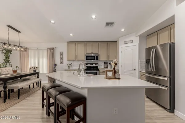 a kitchen with refrigerator a sink and chairs