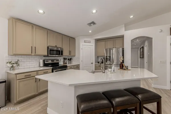 a kitchen with a sink a stove a kitchen island with chairs and cabinets