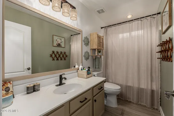 a bathroom with a granite countertop sink a toilet a mirror and shower