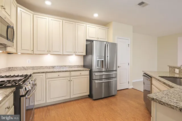 a kitchen with stainless steel appliances granite countertop a stove a refrigerator and a sink