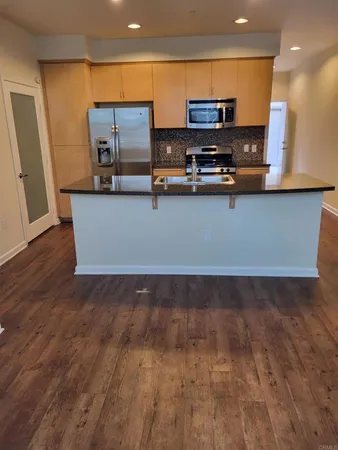 a view of kitchen with stainless steel appliances wooden floor