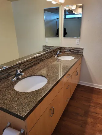 a bathroom with a granite countertop sink a toilet a mirror and shower
