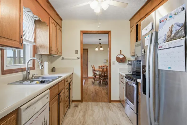 a kitchen with a sink dishwasher a refrigerator and a stove with wooden floor