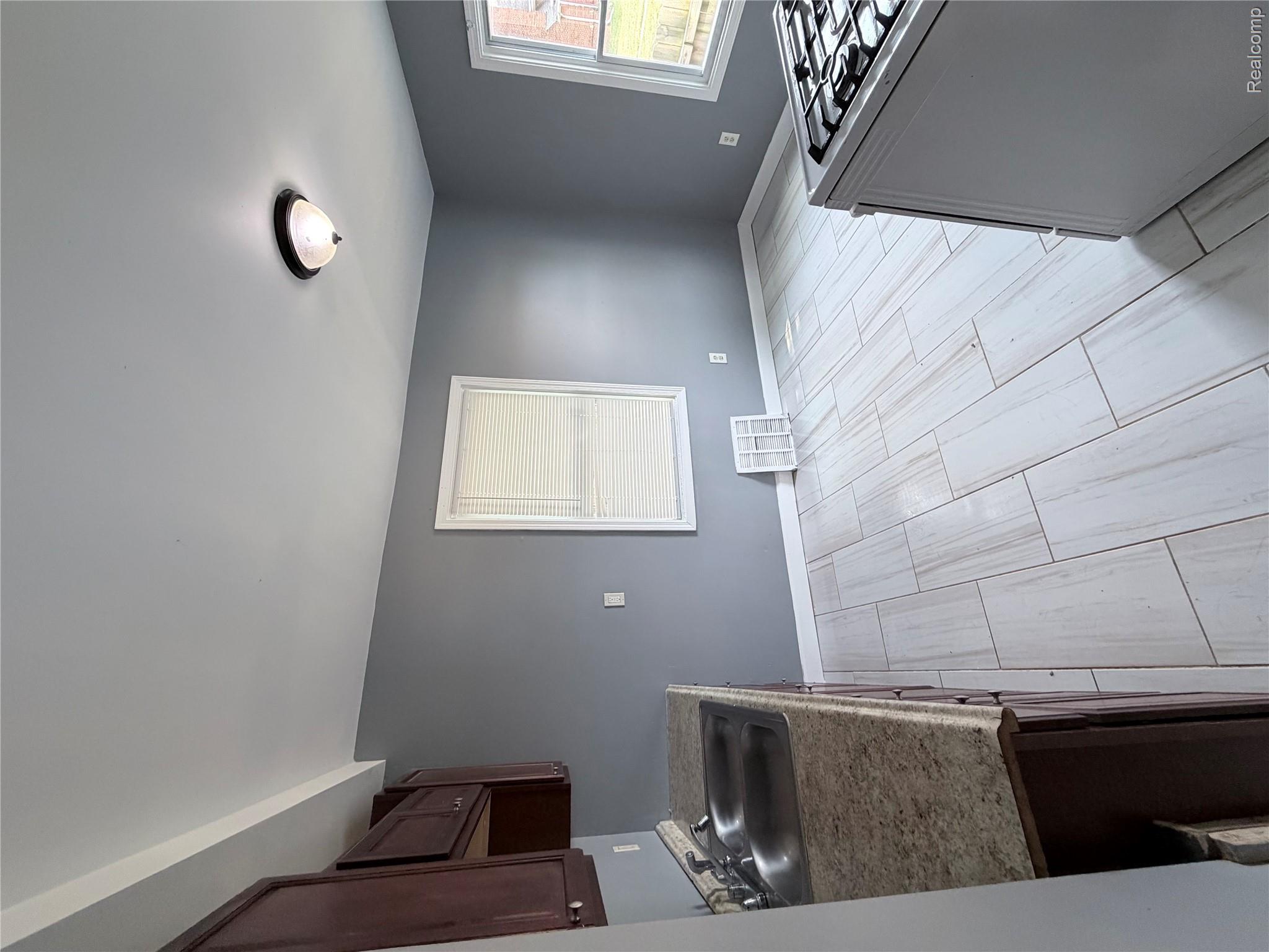14255 Burt Road Detroit, MI 48223 - Photo 4 of 7 Kitchen featuring white tile flooring, dark wood-finish cabinetry, a double basin stainless steel sink, and light-toned countertops