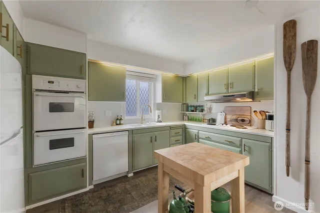 a kitchen with stainless steel appliances kitchen island granite countertop a refrigerator a stove a dining table and chairs with wooden floor