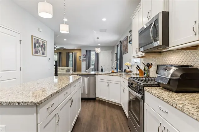 a kitchen with stainless steel appliances granite countertop a refrigerator a sink and a stove top oven