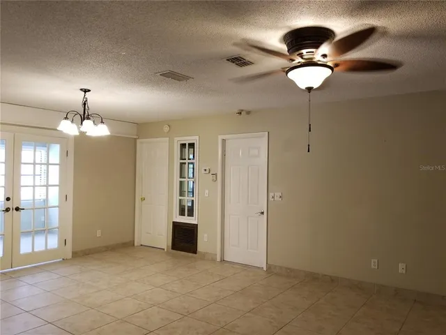 a view of a livingroom with a chandelier fan and windows