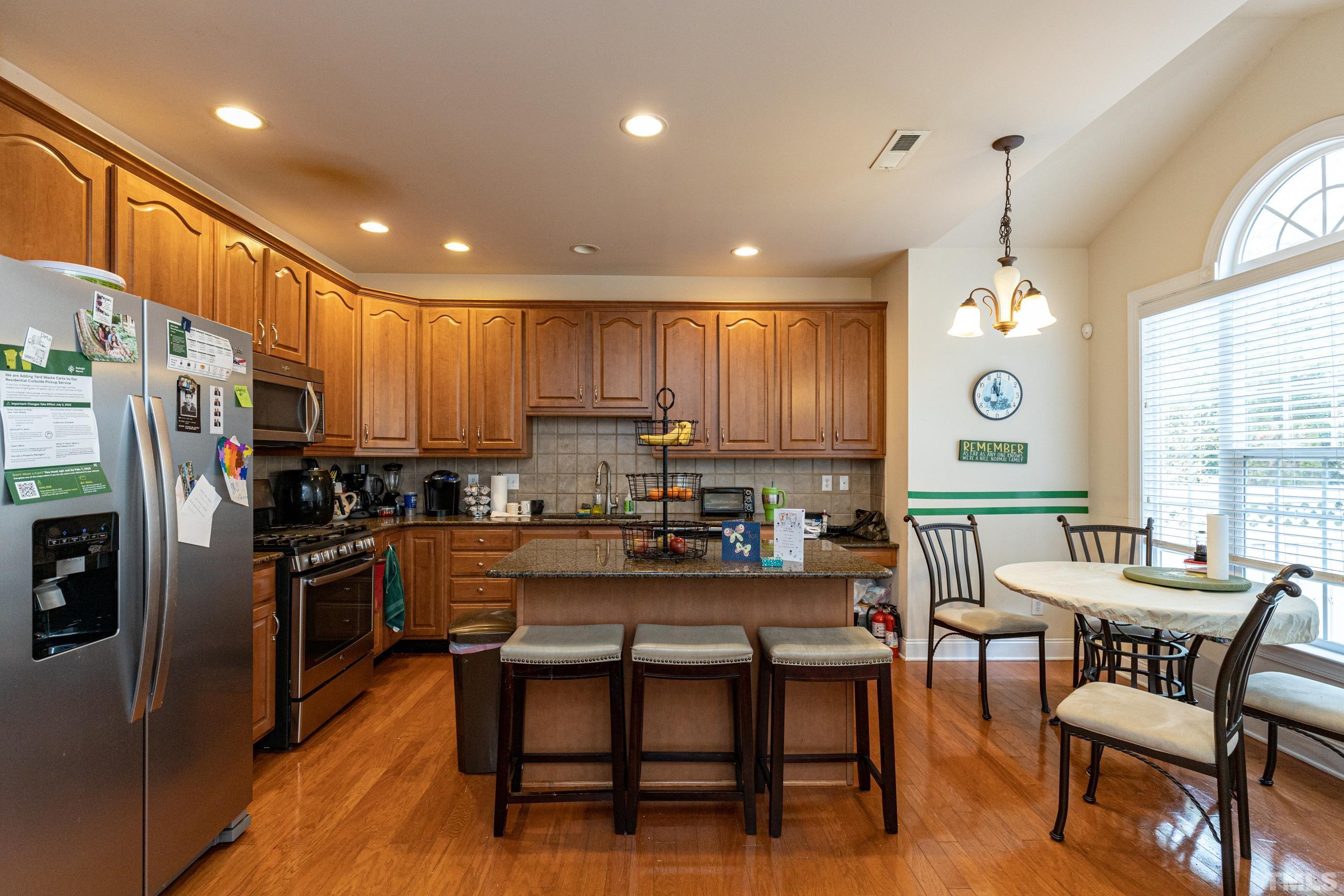 11210 Maplecroft Court Raleigh, NC 27617 - Photo 13 of 30 a kitchen with stainless steel appliances granite countertop a stove top oven a refrigerator a sink dishwasher a dining table and chairs with wooden floor