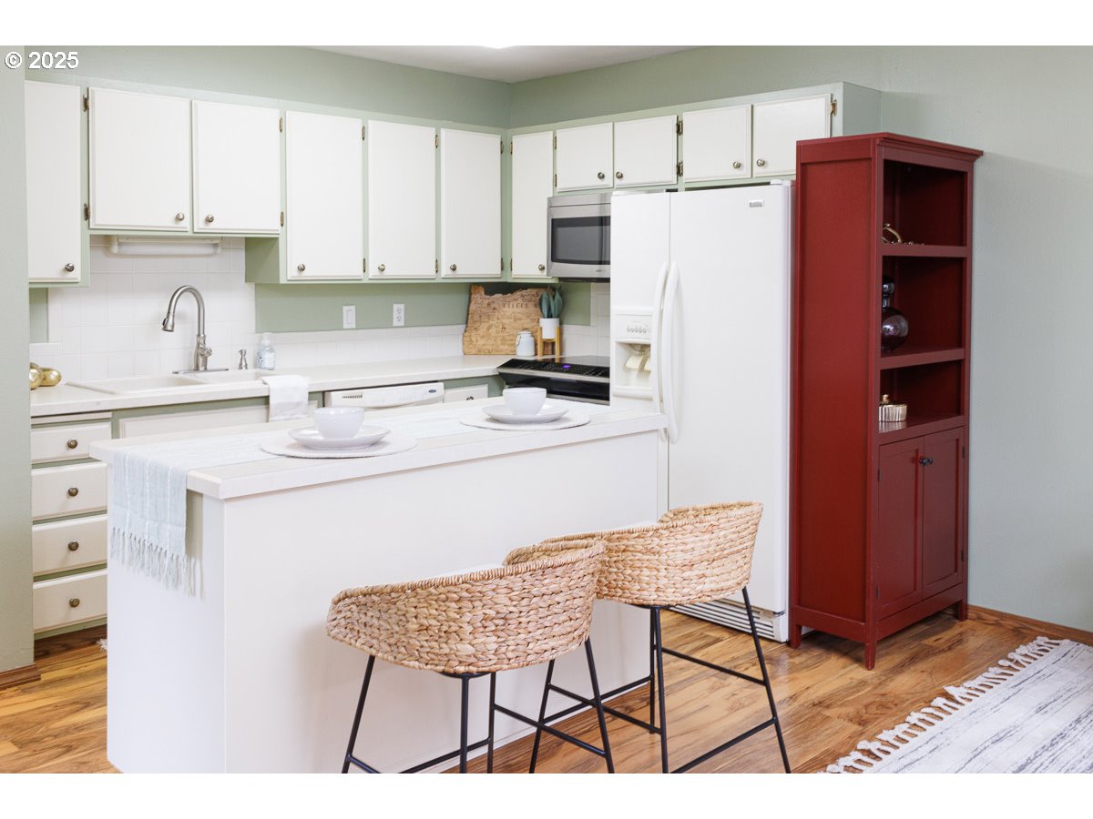490 North Hayden Island Drive, Unit 98 Portland, OR 97217 - Photo 4 of 21 a kitchen with stainless steel appliances a refrigerator a stove a sink and white cabinets with wooden floors