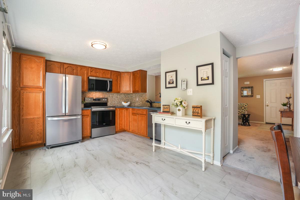 1705 Sundance Drive Reston, VA 20194 - Photo 10 of 29 a kitchen with stainless steel appliances a stove a refrigerator a sink a oven with white cabinets and wooden floor