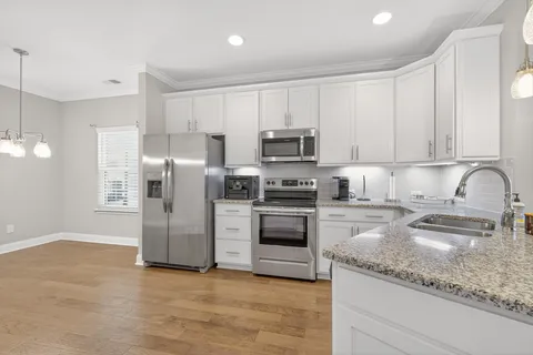 a kitchen with granite countertop a refrigerator sink and white cabinets