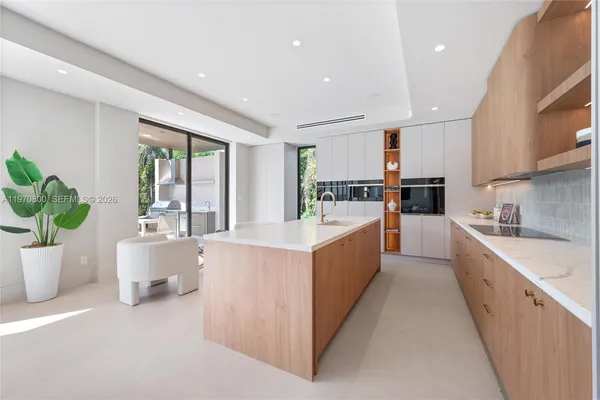 a large white kitchen with kitchen island a potted plant a sink a counter top space and living room view