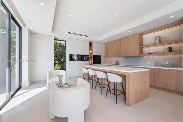a kitchen with stainless steel appliances granite countertop a table chairs sink and cabinets