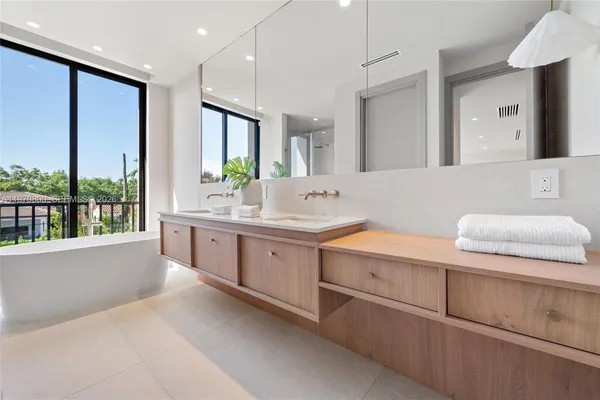 a large white bathroom with a double vanity sink a mirror and a bathtub
