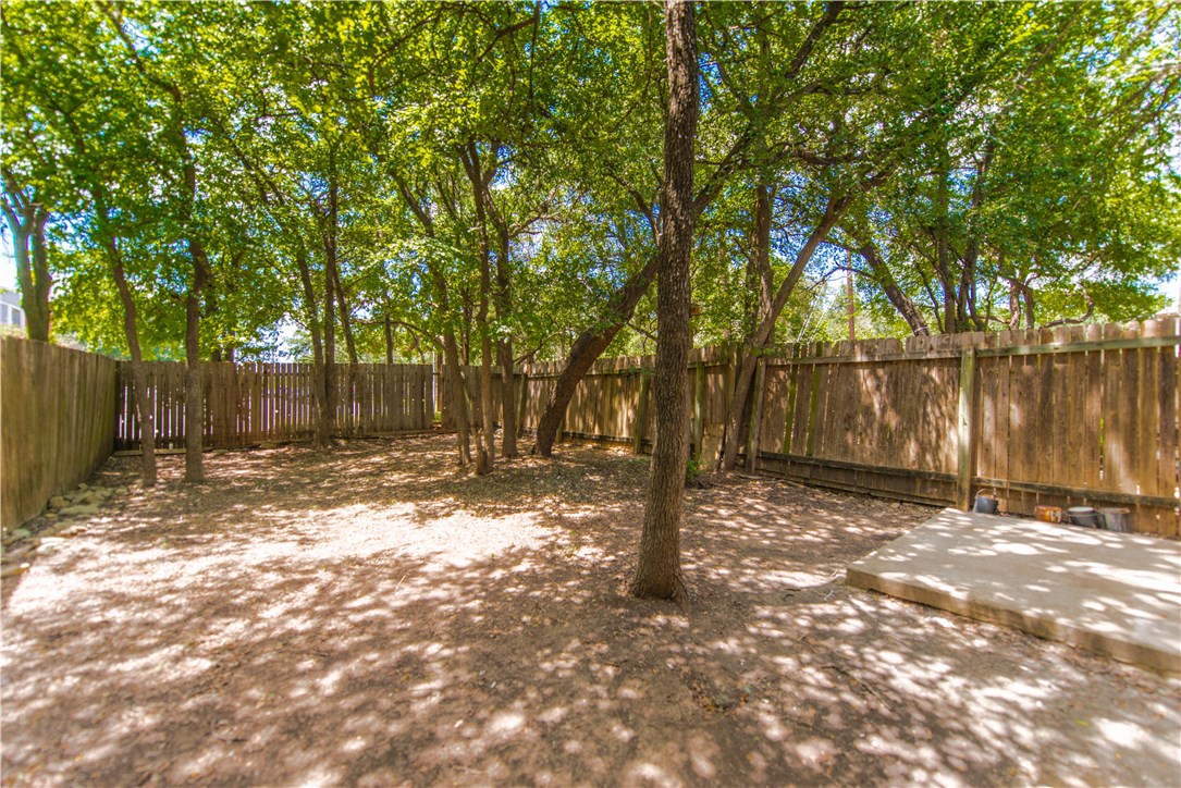 9710 Sugar Hill Drive, Unit A Austin, TX 78748 - Photo 33 of 40 a backyard of a house with large trees and wooden fence