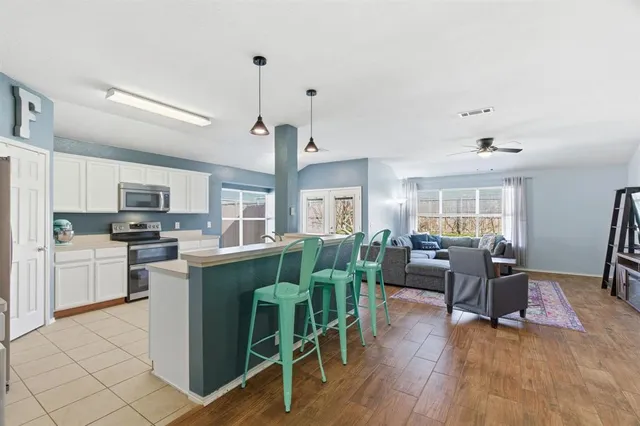 a living room with furniture kitchen view and a wooden floor