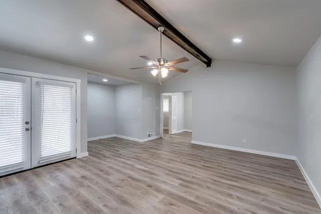 an empty room with wooden floor fan and windows