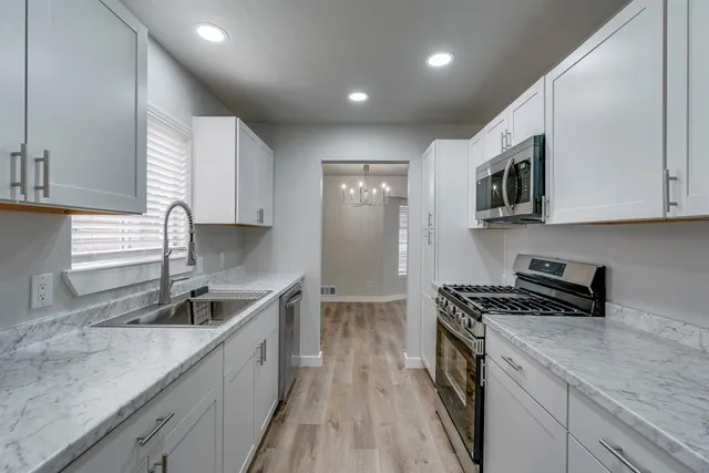 a kitchen with stainless steel appliances granite countertop a sink stove and cabinets