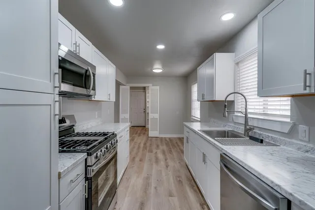 a kitchen with granite countertop stainless steel appliances a sink stove top oven and cabinets