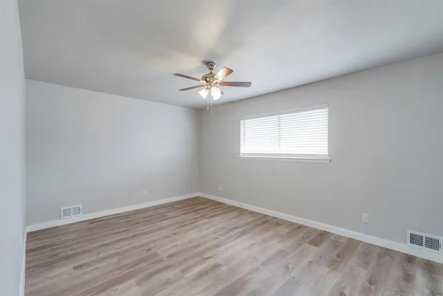 a view of a room with wooden floor and a ceiling fan