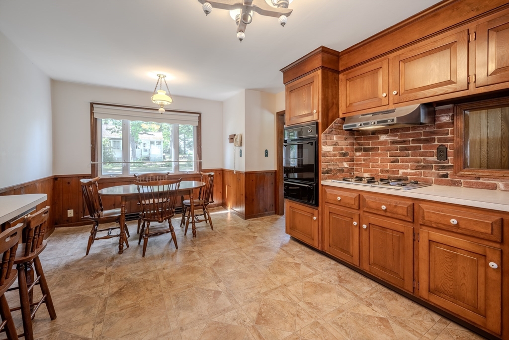 10 Primrose Road Billerica, MA 01821 - Photo 6 of 37 a kitchen with granite countertop cabinets a dining table and chairs a refrigerator with wooden floors