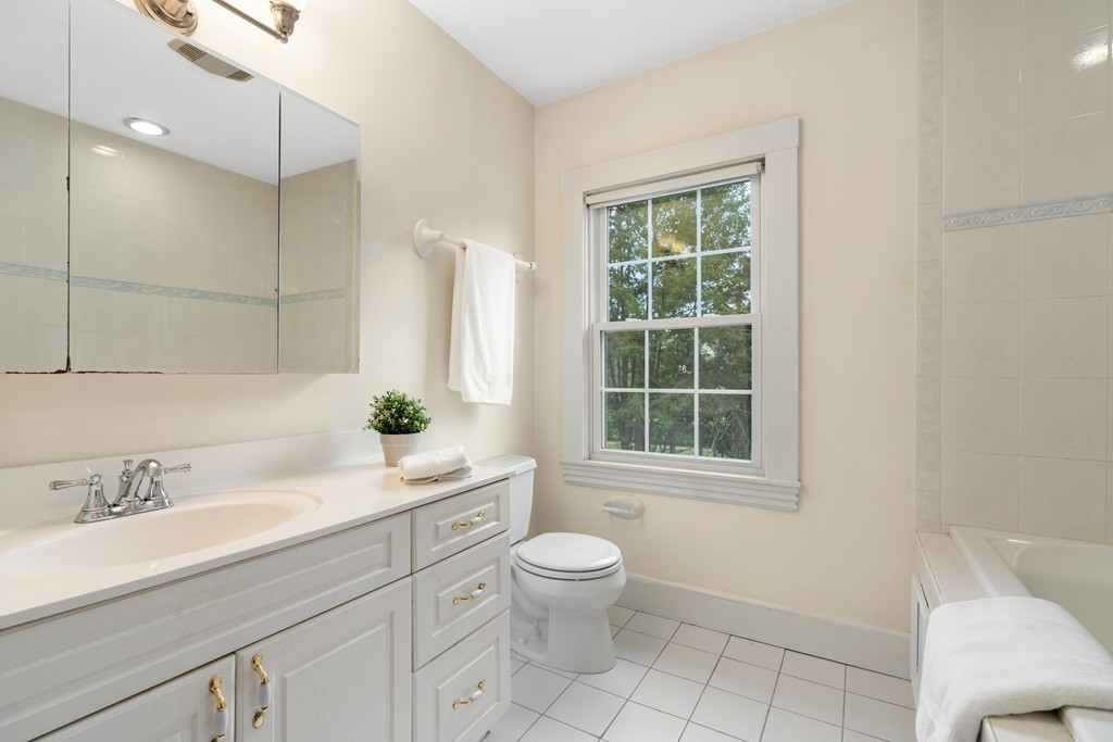 8-10 Upland Road Wellesley, MA 02482 - Photo 11 of 24 a bathroom with a granite countertop toilet a sink a mirror a window and shower