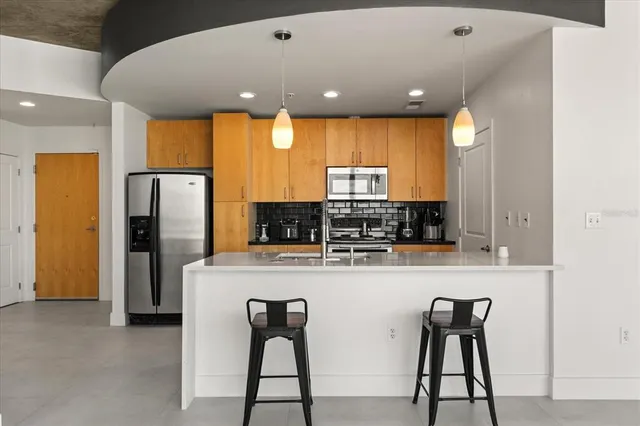 a kitchen with stainless steel appliances kitchen island granite countertop a refrigerator a stove a microwave oven with white cabinets and wooden floor