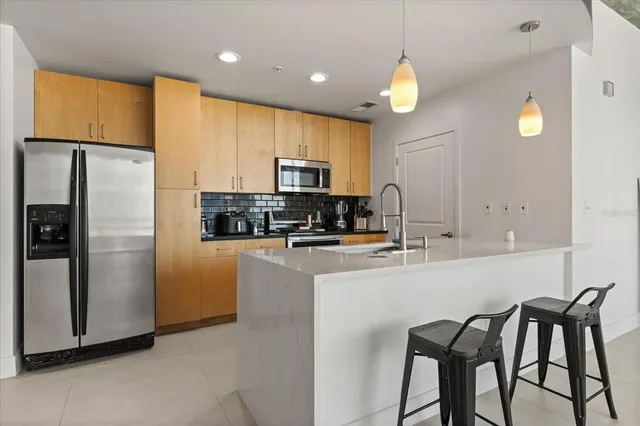 a kitchen with stainless steel appliances granite countertop a stove a refrigerator a sink a microwave a dining table and chairs with wooden floor