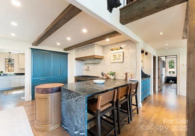 a kitchen with stainless steel appliances granite countertop a table chairs and a refrigerator