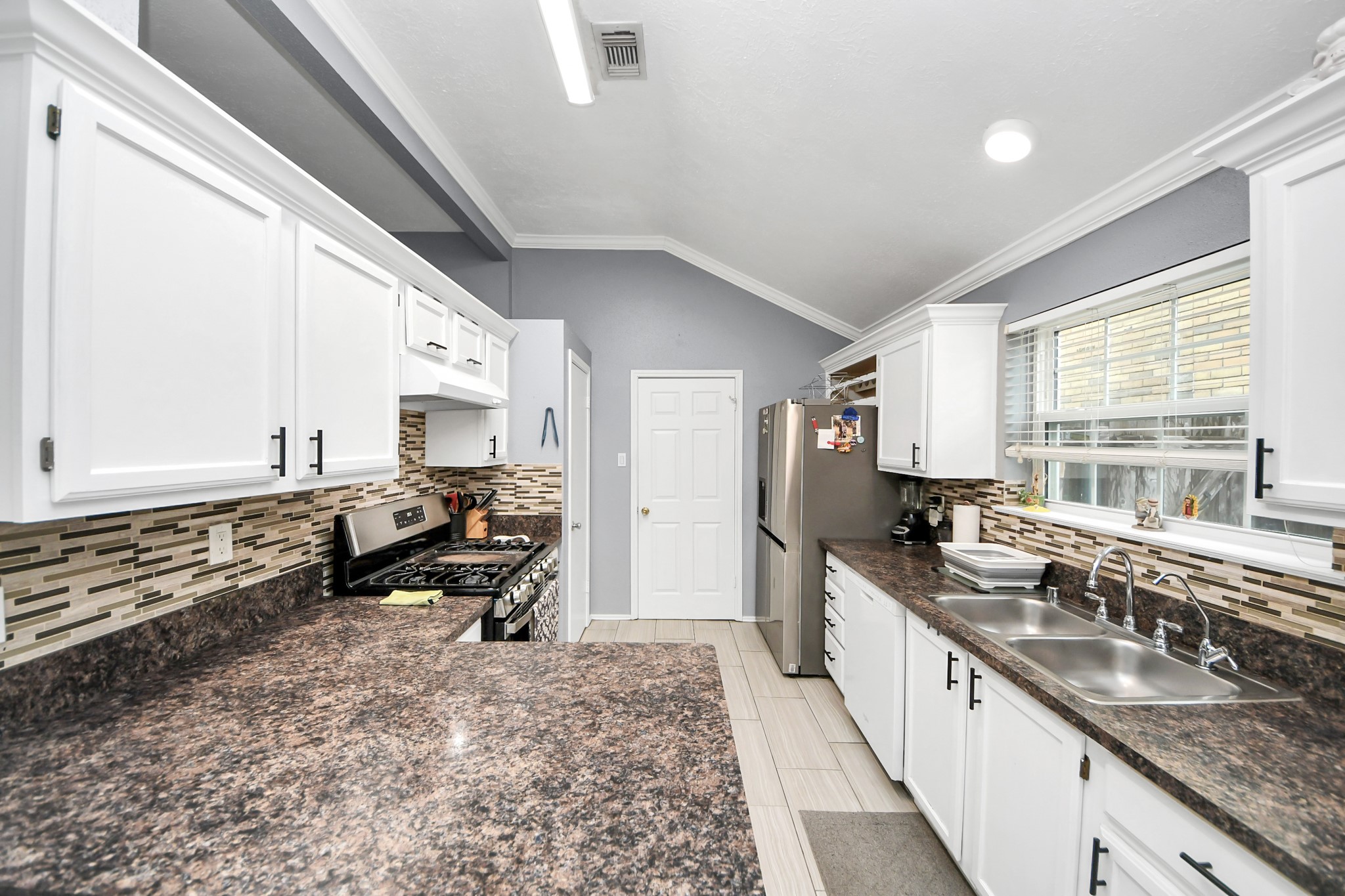 17702 Poppy Trails Lane Houston, TX 77084 - Photo 16 of 37 a large kitchen with kitchen island granite countertop a large window and stainless steel appliances
