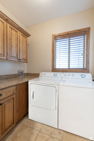 382 Ridgeview Street, Unit 8 & 9 Brian Head, UT 84719 - Photo 39 of 52 Laundry area featuring wood-finish cabinetry with dark hardware, a stone-finish countertop, and tiled flooring