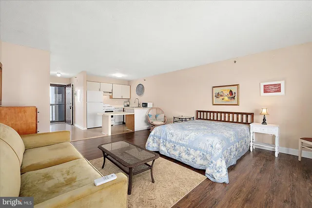 a bedroom with a bed couch and a view of kitchen