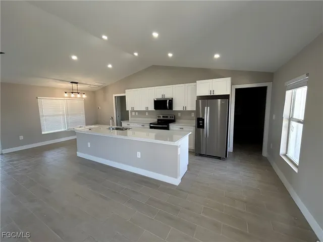 a large kitchen with stainless steel appliances a refrigerator and a stove top oven