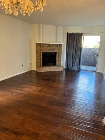 an empty room with wooden floor fireplace and windows