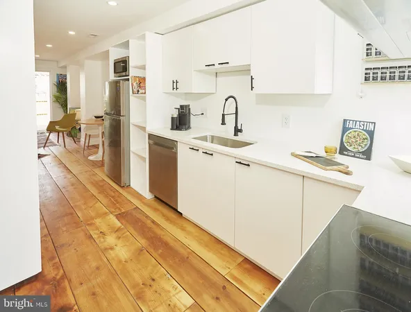 a kitchen with stainless steel appliances a refrigerator a sink a stove and white cabinets