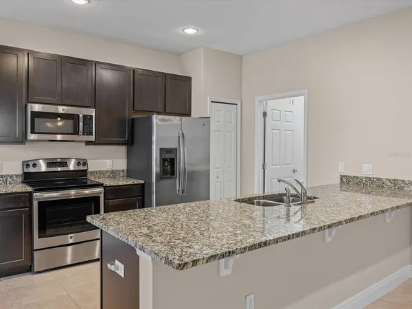 a kitchen with kitchen island granite countertop a sink stove and refrigerator