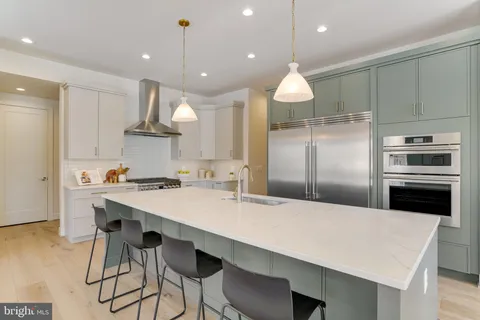 a kitchen with stainless steel appliances a dining table chairs sink and cabinets