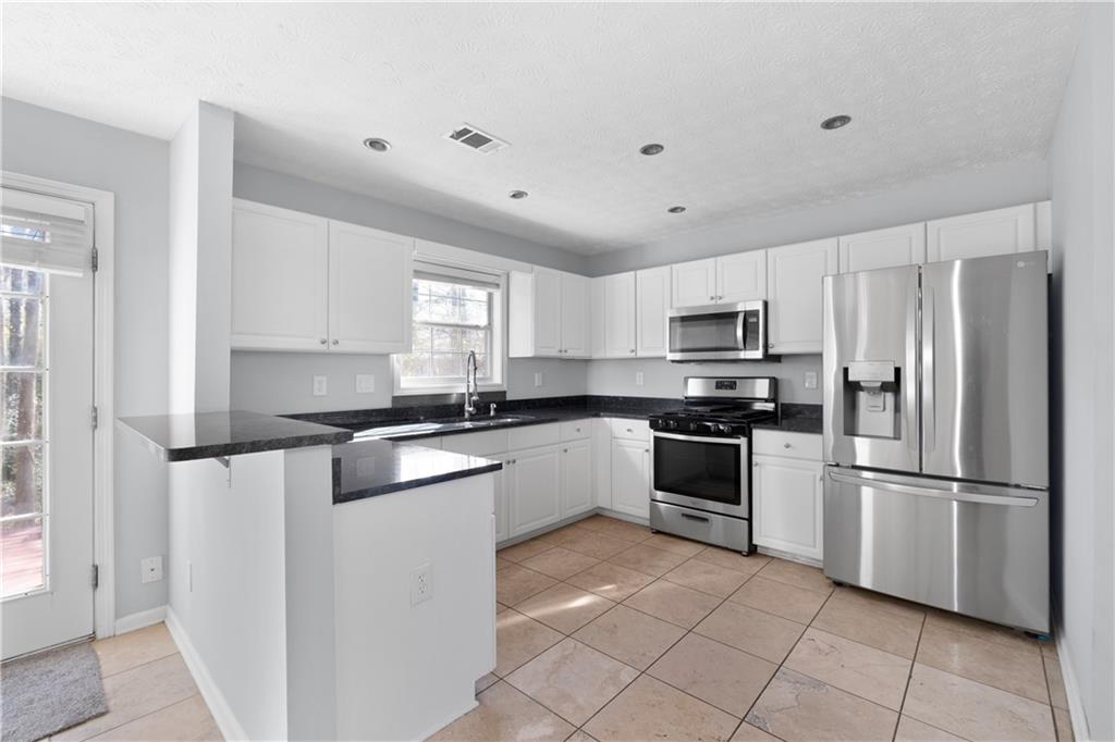 4240 Berkeley Mill Lane Duluth, GA 30096 - Photo 11 of 32 a kitchen with granite countertop white cabinets and stainless steel appliances