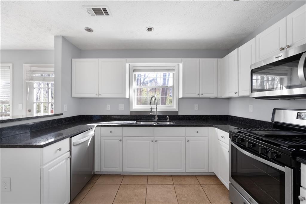 4240 Berkeley Mill Lane Duluth, GA 30096 - Photo 12 of 32 a kitchen with granite countertop white cabinets and appliances