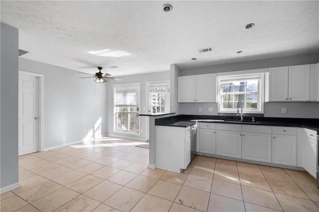 a large kitchen with granite countertop white cabinets a sink a window and stainless steel appliances