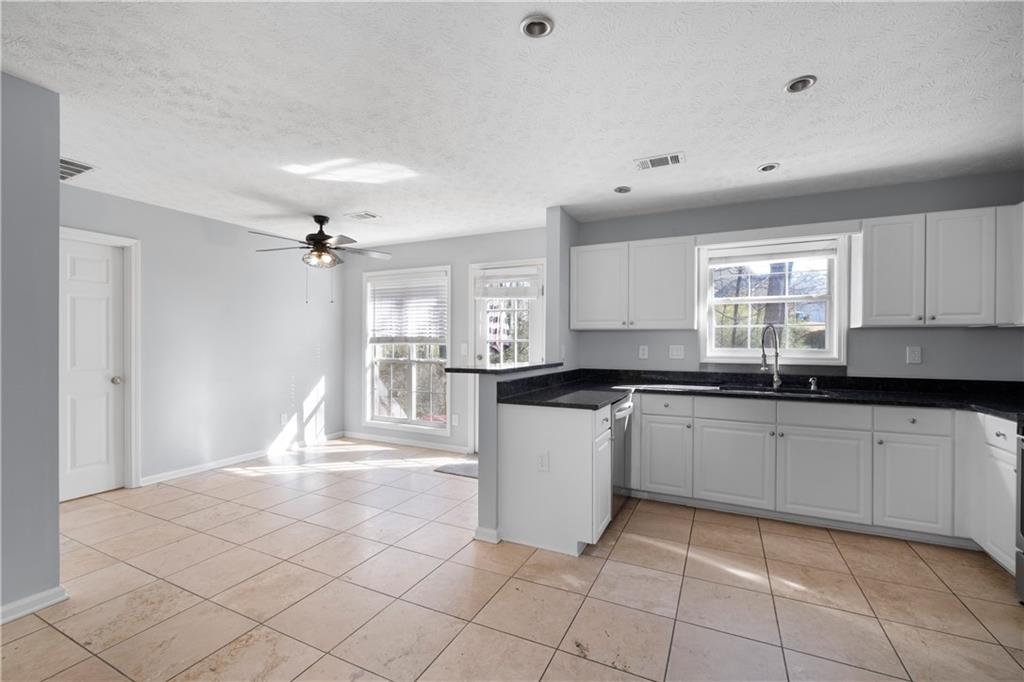 4240 Berkeley Mill Lane Duluth, GA 30096 - Photo 9 of 32 a large kitchen with granite countertop white cabinets a sink a window and stainless steel appliances