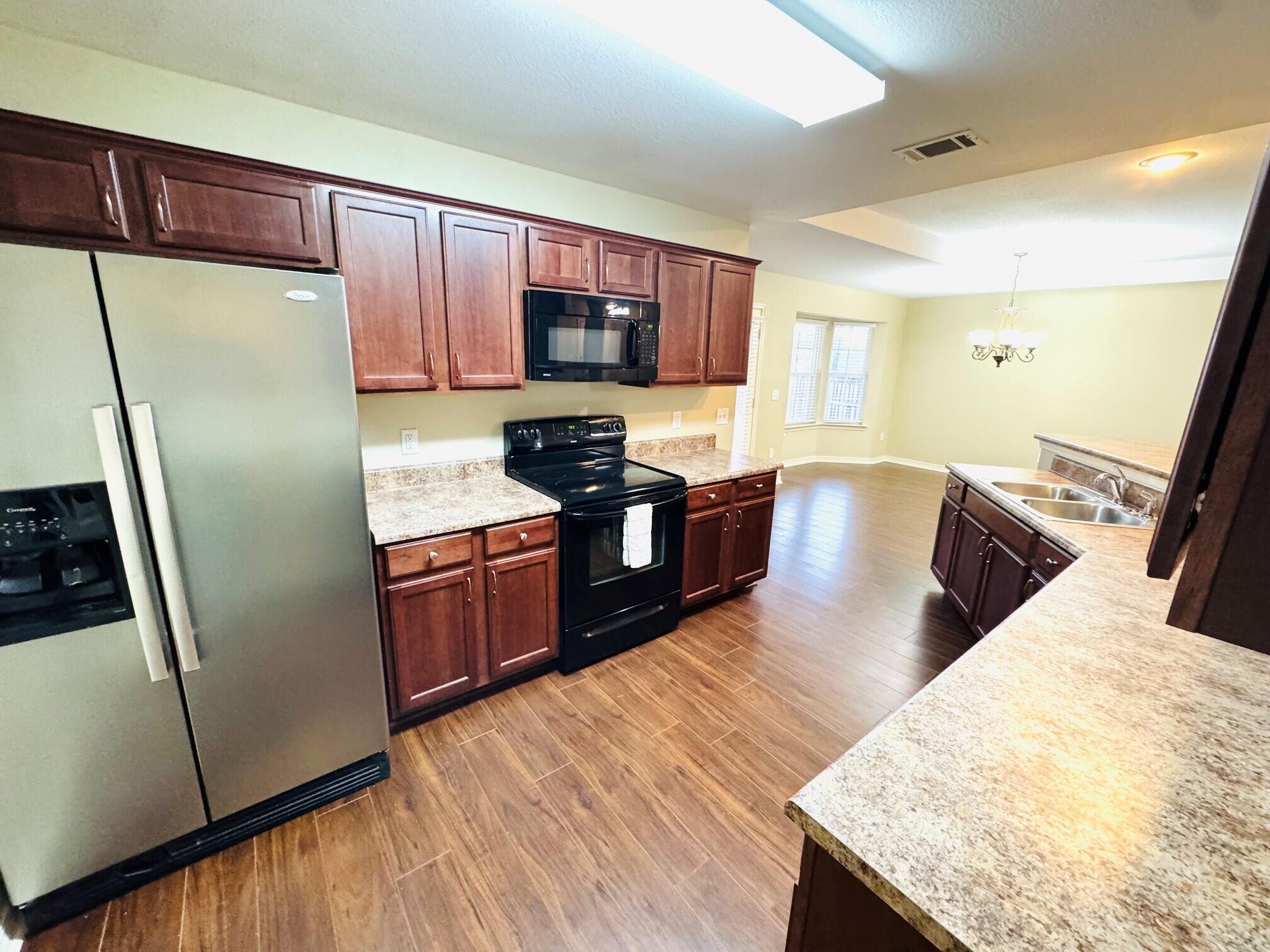 594 Hunters Ridge Road DeFuniak Springs, FL 32433 - Photo 6 of 17 a kitchen with stainless steel appliances granite countertop a refrigerator a stove and a sink with wooden floors