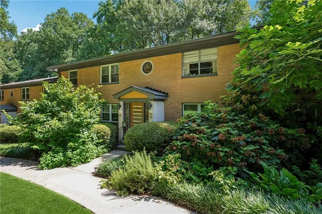 a backyard of a house with large trees and plants