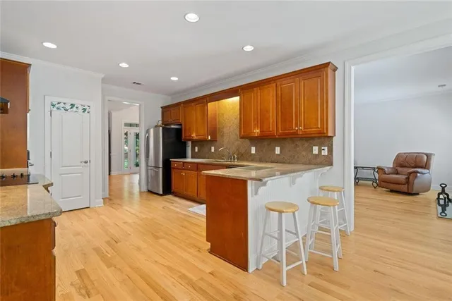 a open kitchen with stainless steel appliances granite countertop a refrigerator a sink a stove and island with wooden floor