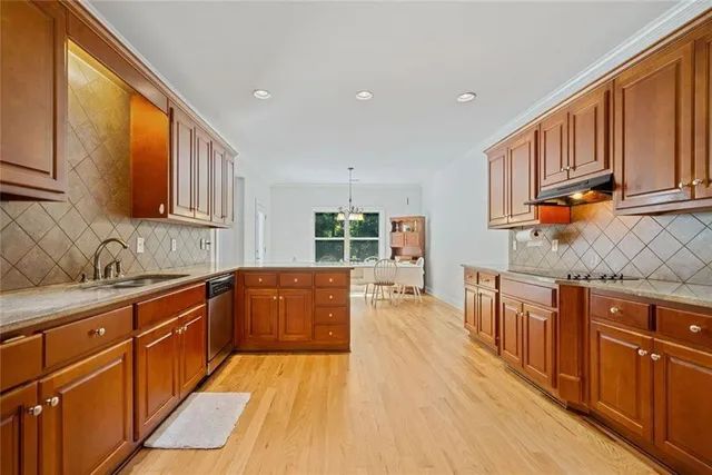 a large kitchen with stainless steel appliances wooden cabinets a stove and a sink