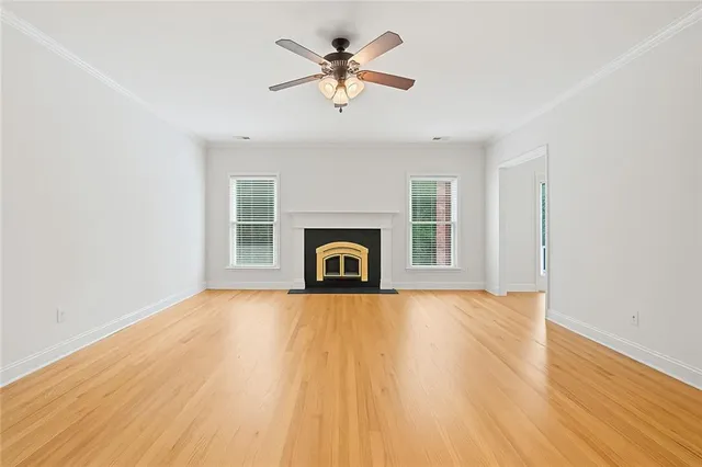 an empty room with chandelier fan and wooden floor