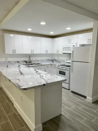 a kitchen with stainless steel appliances granite countertop a sink a stove a refrigerator and white cabinets