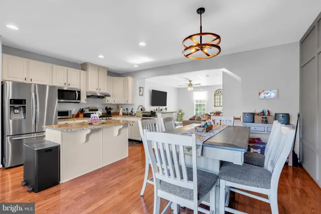 a kitchen with stainless steel appliances granite countertop a stove refrigerator a dining table and chairs with wooden floor